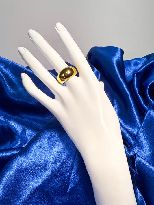 Mannequin hand wearing a gold ring on blue satin fabric